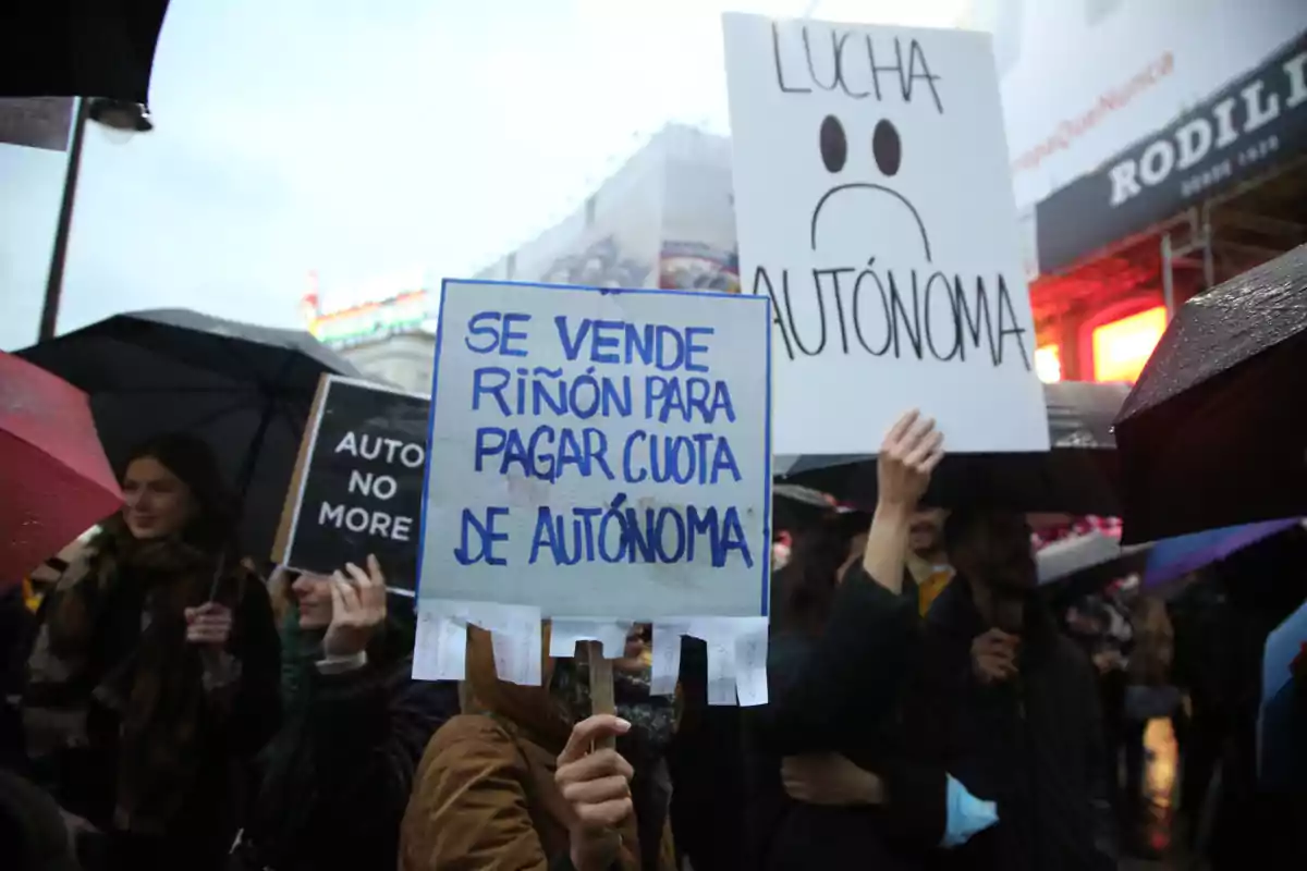 Persones manifestant-se sota la pluja amb pancartes que expressen descontentament per la situació dels treballadors autònoms