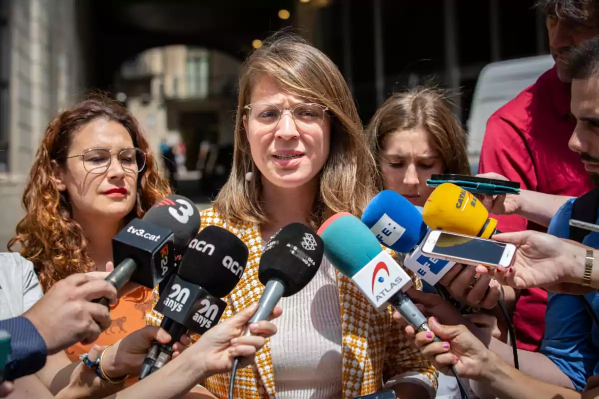 Janet Sanz, dels Comuns, parlant davant de diversos micròfons de diferents mitjans de comunicació.