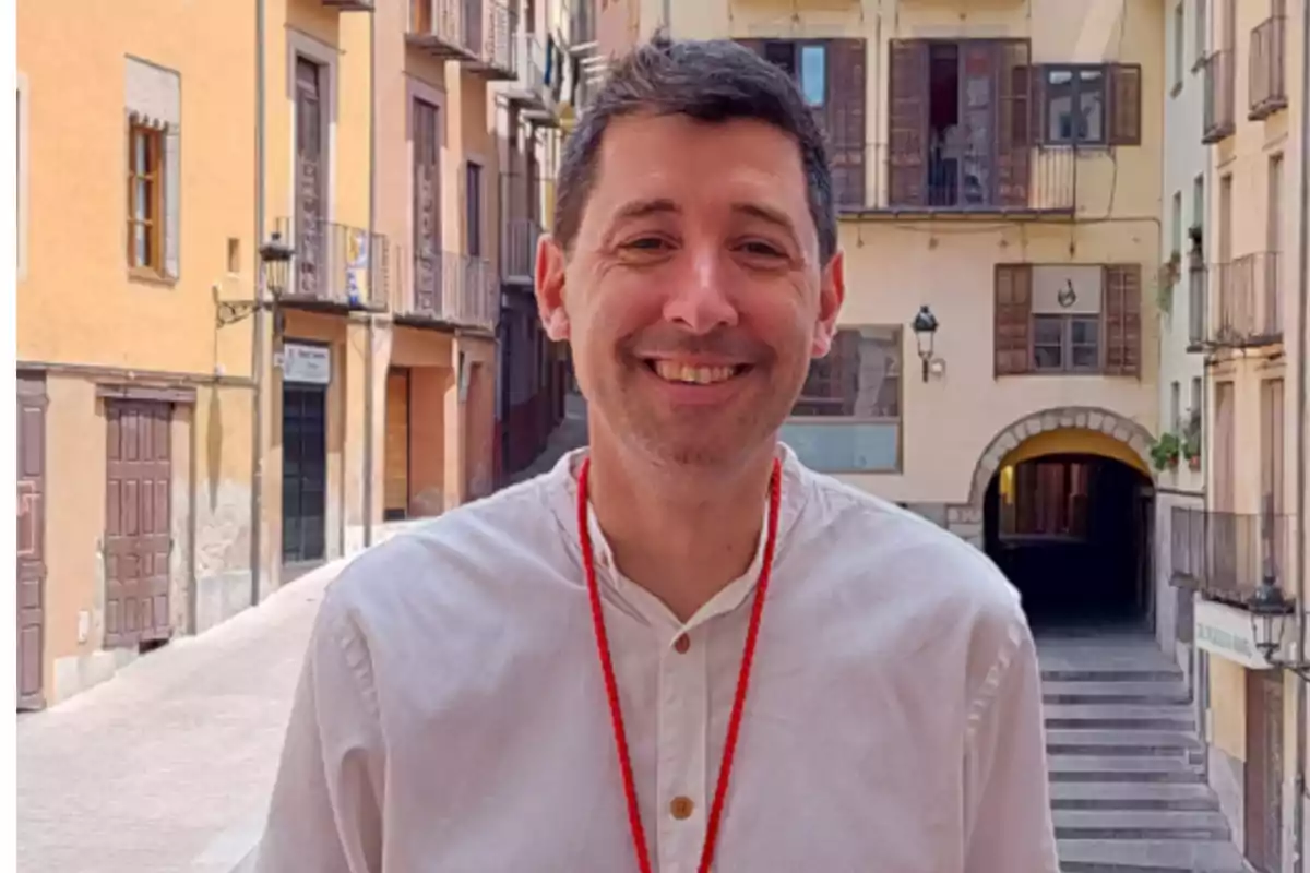 L'alcalde de Berga, Ivan Sànchez i Rodriguez, somrient amb camisa blanca i collaret vermell en un carrer amb edificis antics.