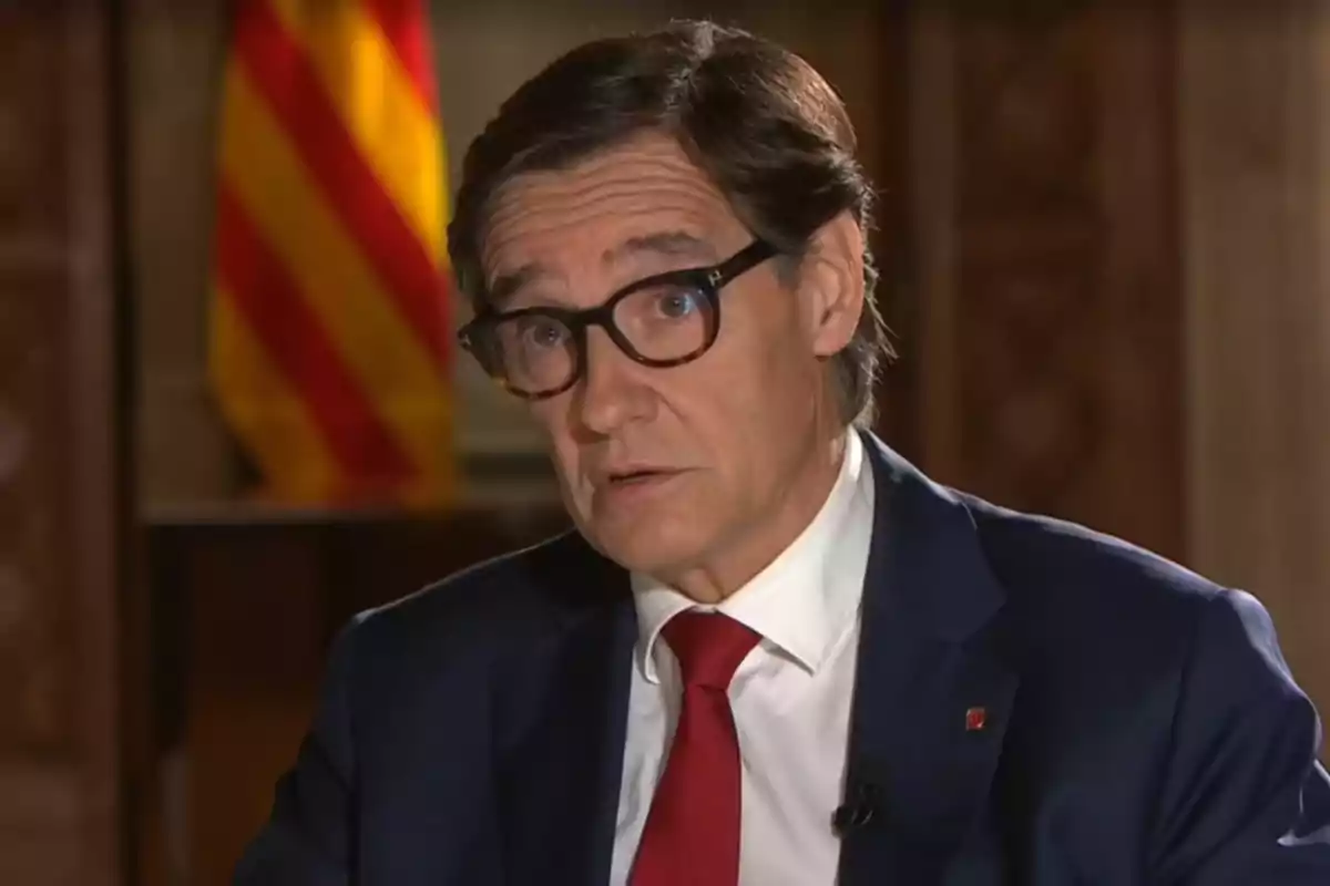 Salvador Illa, president de la Generalitat, donant una entrevista, amb una bandera catalana al fons.