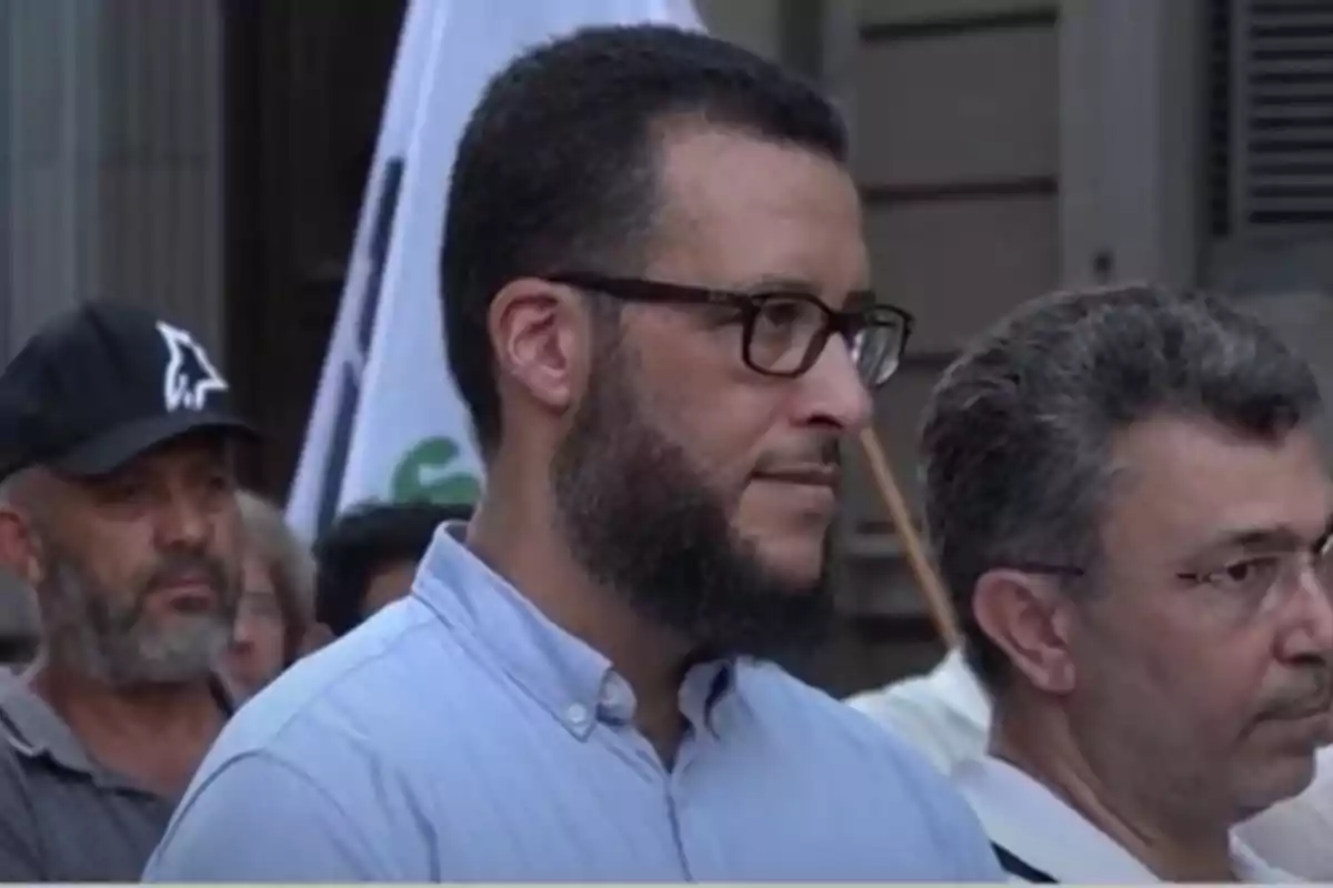 Homes en una manifestació amb banderes al fons.