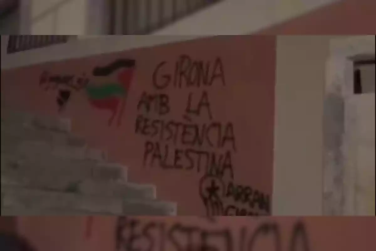 Un grafit en una paret amb el text "Girona amb la resistència palestina" i una bandera palestina pintada al costat.