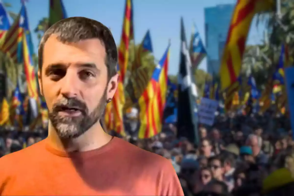 Jordi Borràs està en primer pla, mentre que al fons s'hi observa una multitud amb banderes acolorides.