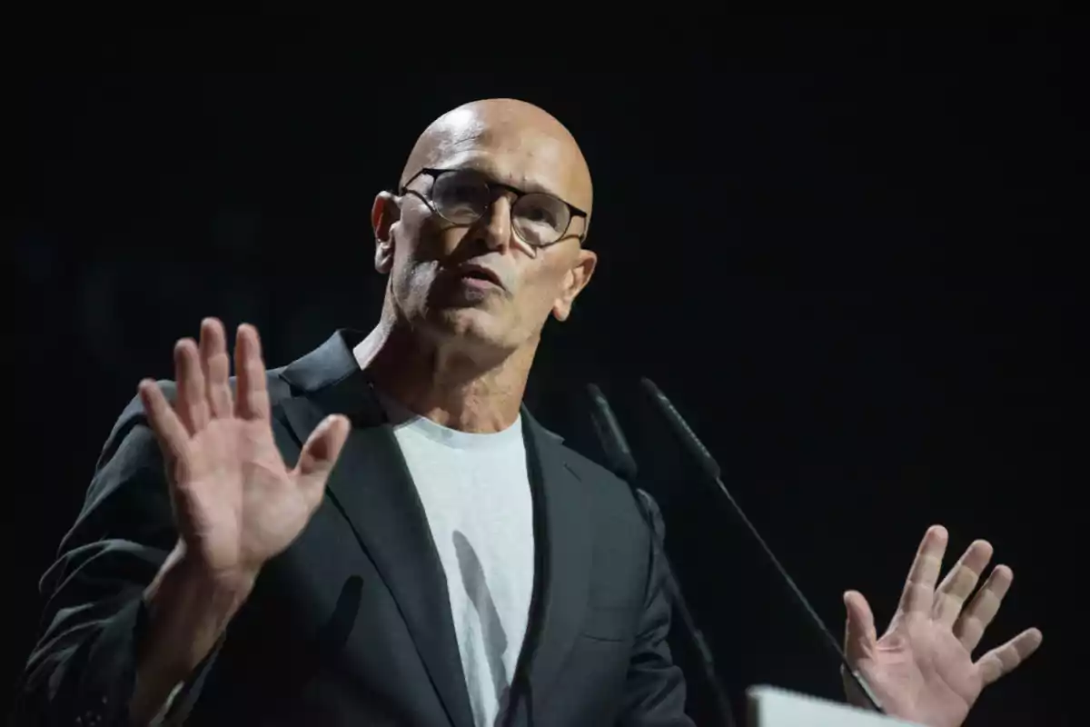 Raül Romeva gesticula mentre parla en un escenari il·luminat.