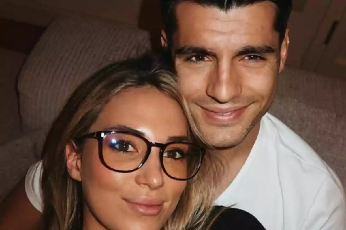 A queda de Alice Camello e Varo Morata sorrindo e sentados no sofá da casa.