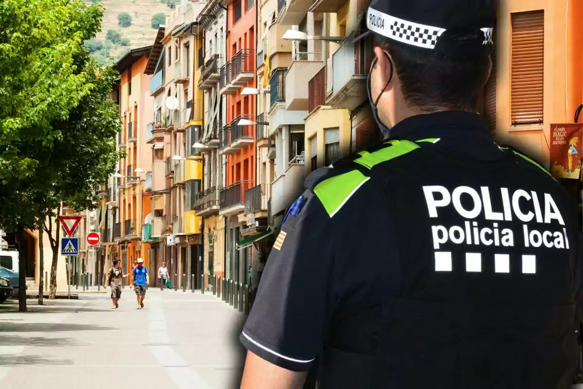 Un policia local d?esquena observa un carrer amb edificis colorits i algunes persones caminant.