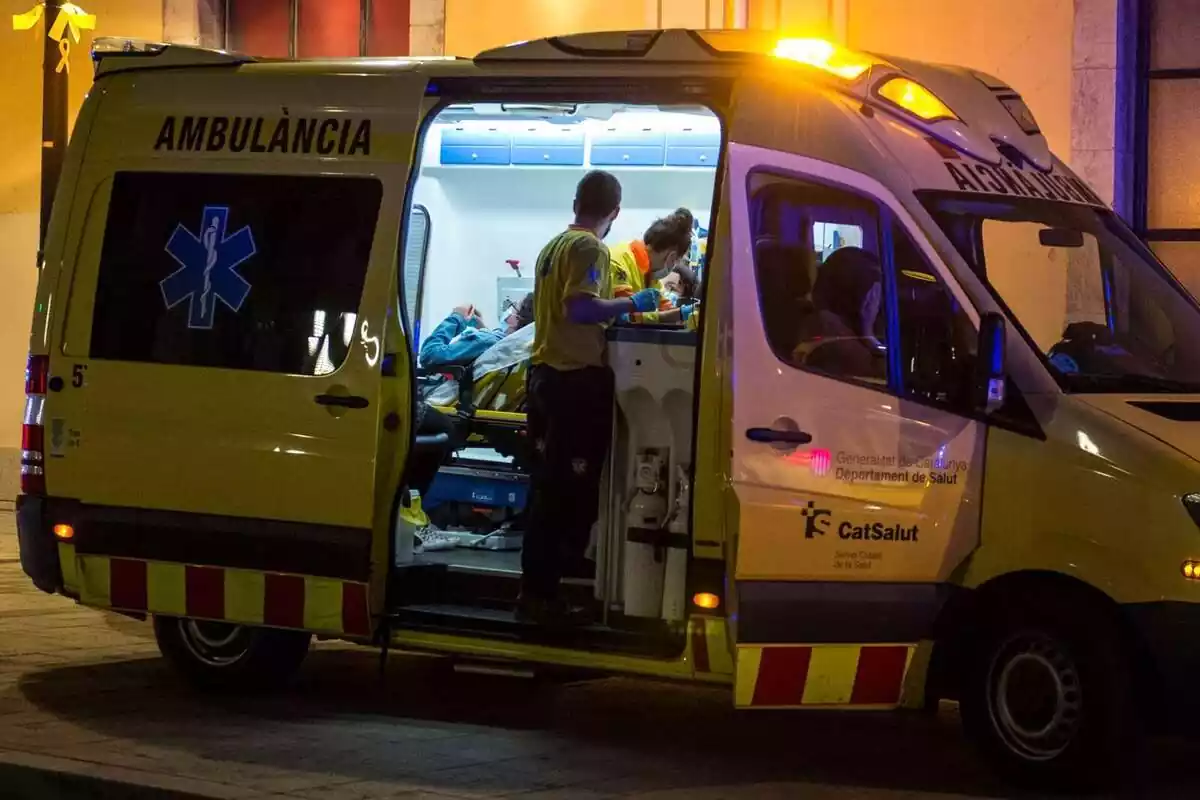 Plànol general d'una ambulància de nit atenent una persona ferida a Girona