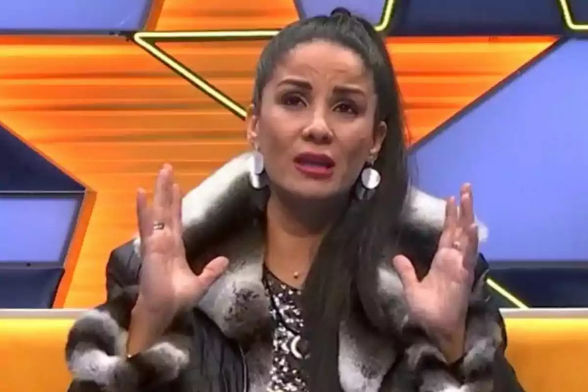 Ana Herminia con expresión emocional en un set de televisión con fondo de estrellas naranjas y azules en GH DÚO.