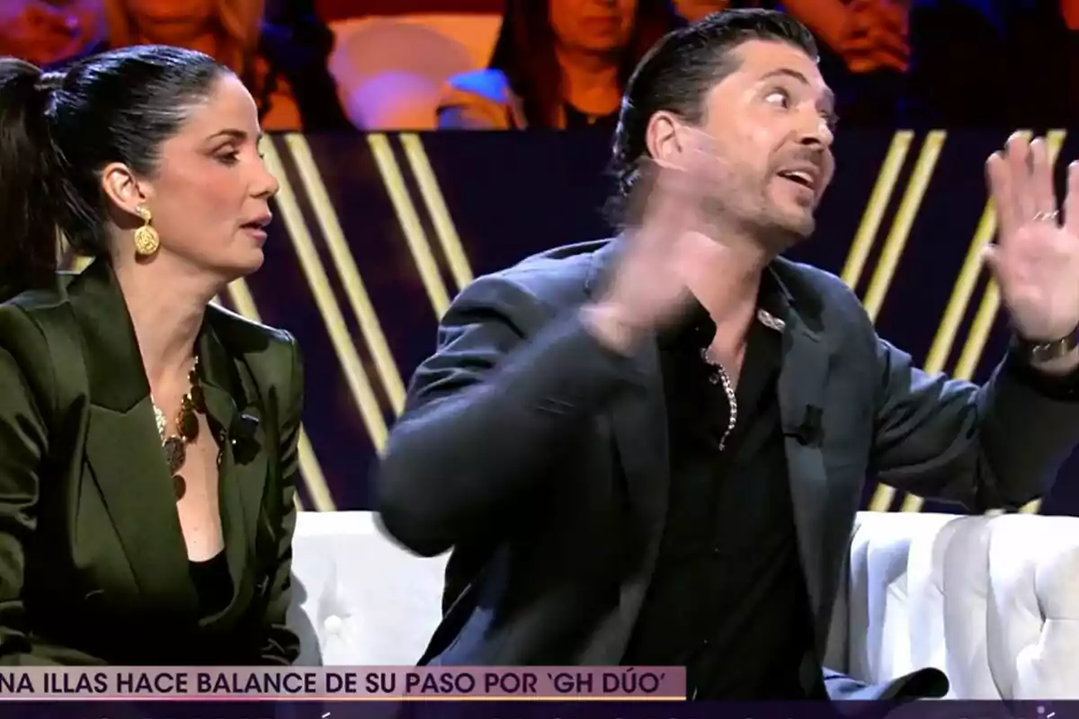 Dues persones estan assegudes en un plató de televisió de De Viernes, Ángel Cristo JR gesticula amb les mans mentre Ana Herminia escolta atentament. Dues persones estan assegudes en un plató de televisió de De Viernes, Ángel Cristo JR gesticula amb les mans mentre Ana Herminia escolta atentament.