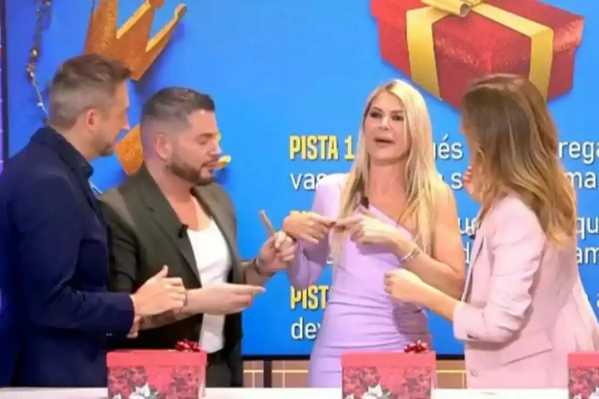 Verónica Dulanto, Frank Blanco, Ana Luque y Alberto Dugarte interactúan en Fiesta con un fondo azul y cajas de regalo rojas sobre una mesa.