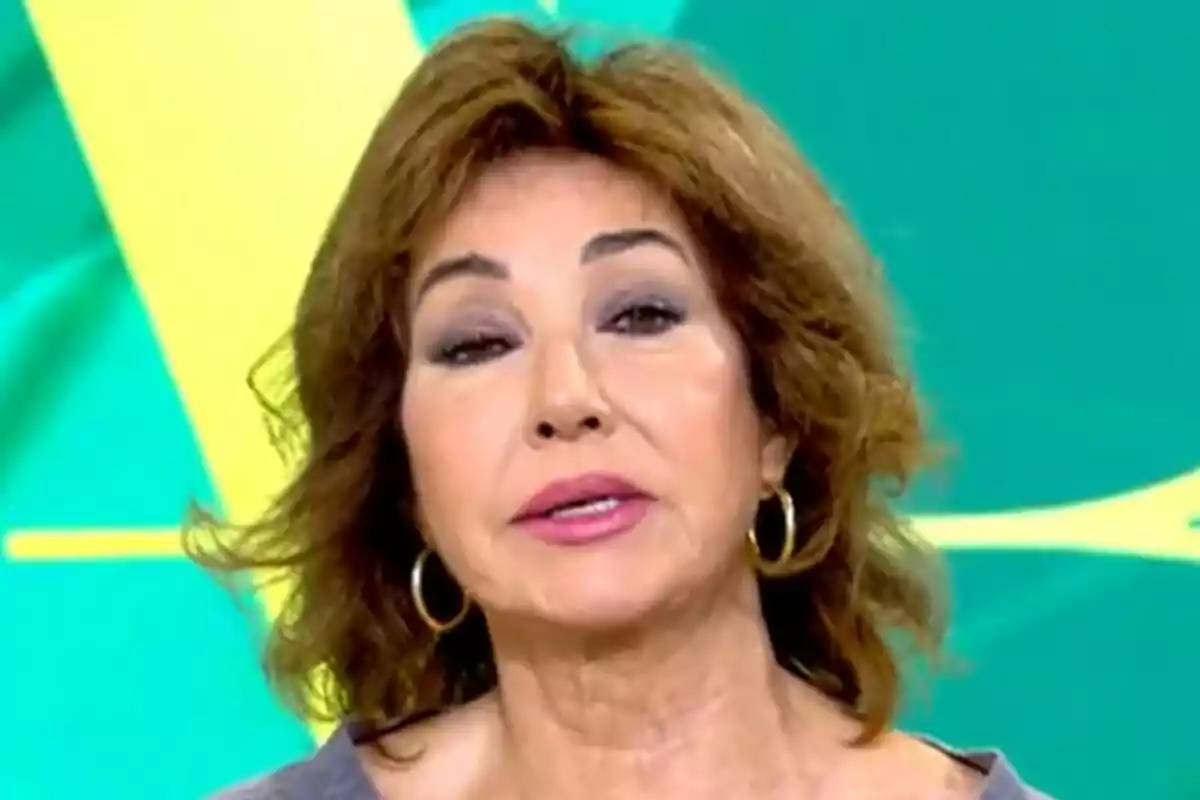 Ana Rosa Quintana with brown hair and gold earrings in front of a green and yellow background on El Programa de Ana Rosa.