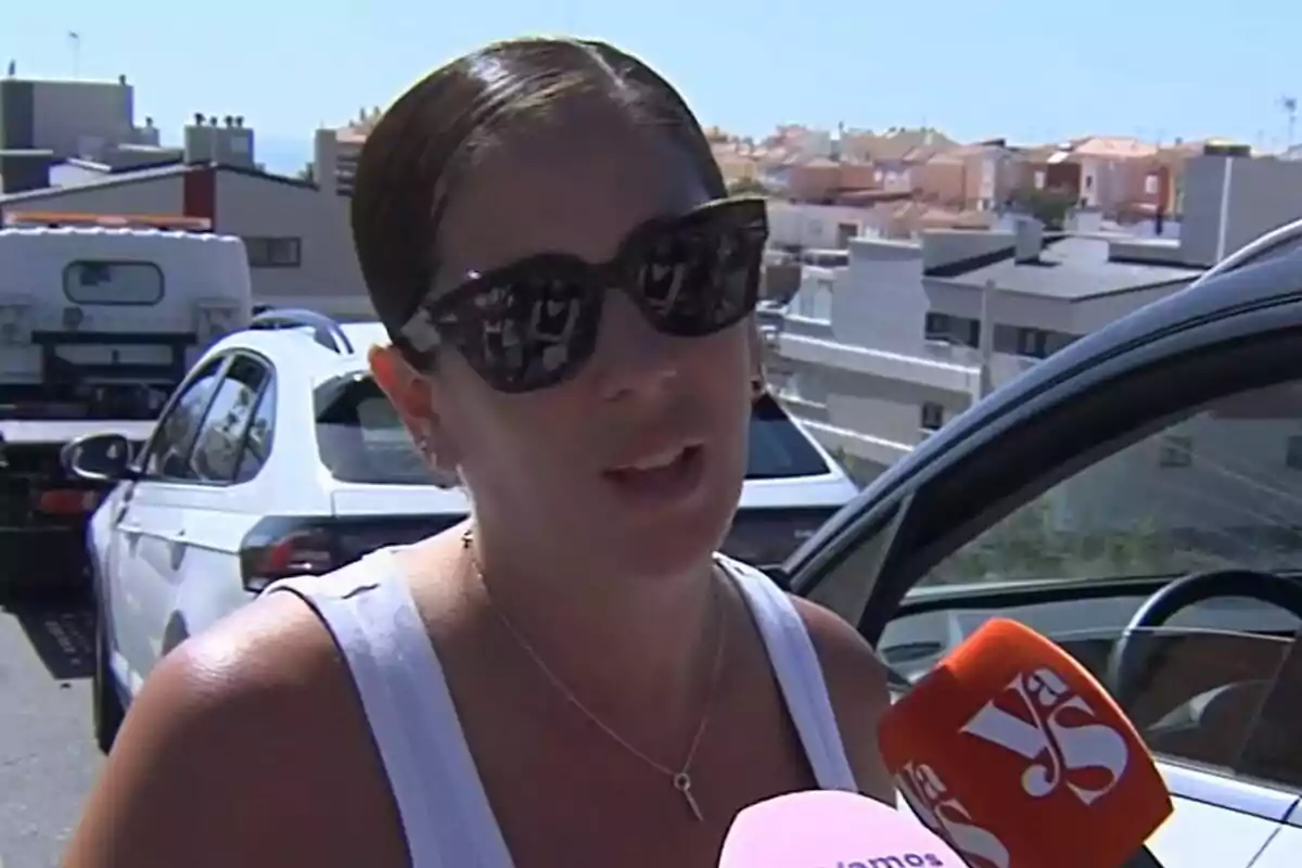 Anabel Pantoja con gafas de sol habla frente a varios micrófonos de Vamos a ver en una calle con coches y edificios al fondo.