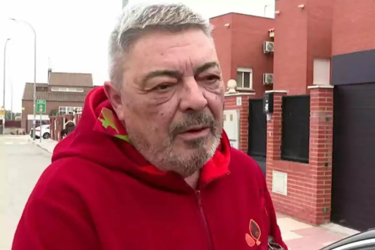 Antonio Canales con sudadera roja de pie en una calle residencial.