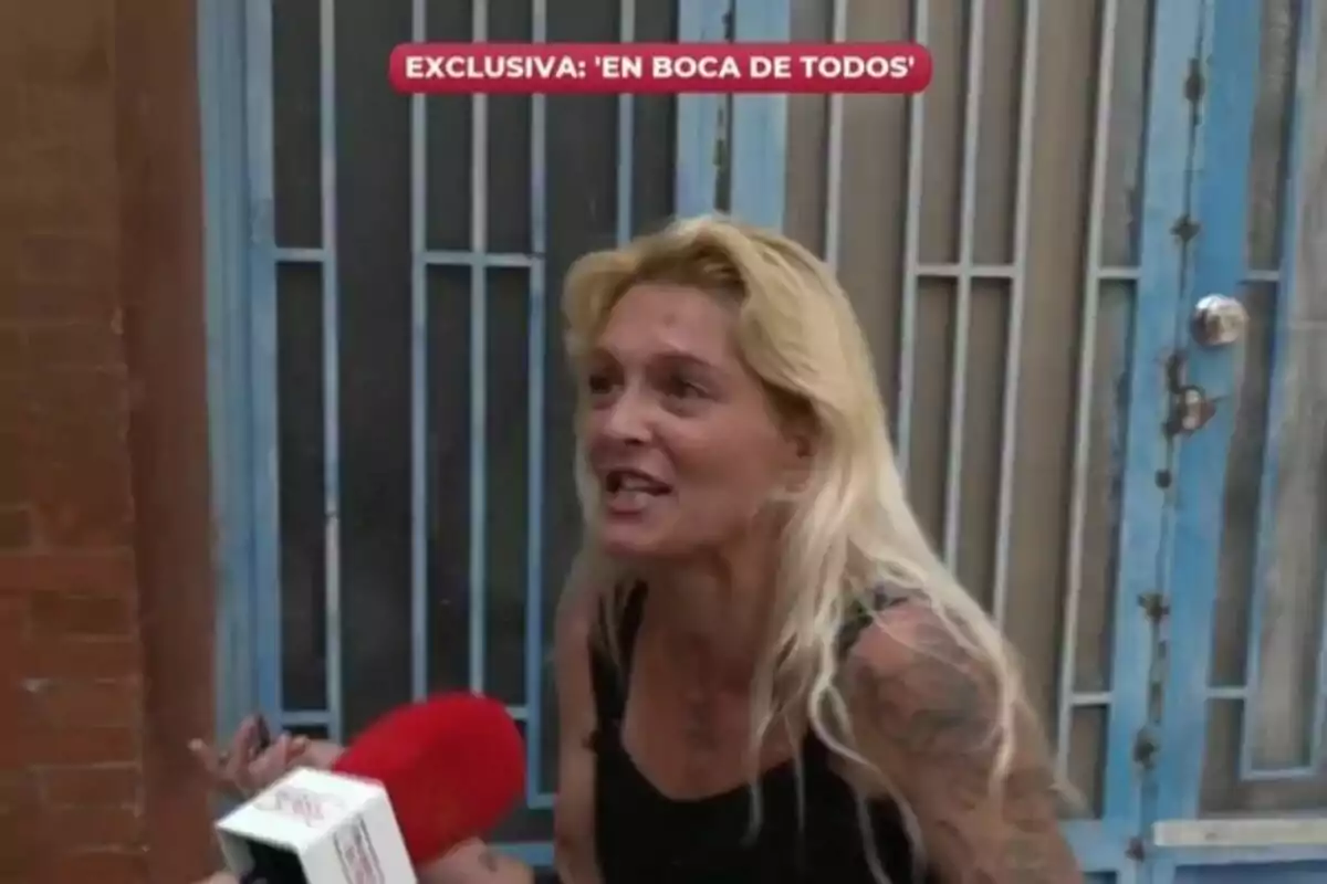 Captura d'una dona rossa amb tatuatges sent entrevistada per En boca de todos davant una porta blava.