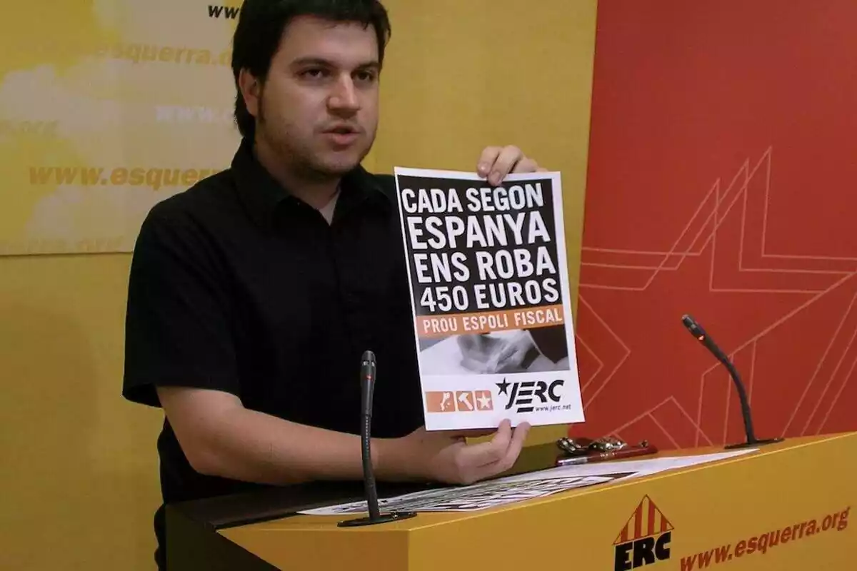 pla mig de Pere Aragonès parlant i sostenint un cartell de JERC on posa "cada segon Espanya ens roba 450 euros"