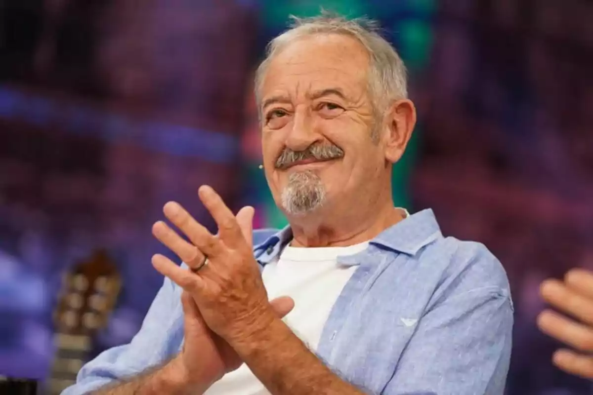 Karlos Arguiñano amb barba i bigoti somriu i aplaudeix mentre està assegut en un ambient colorit a 'El Hormiguero'.