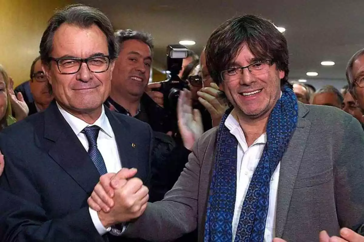 Artur Mas amb Carles Puigdemont donant-se la mà amb fotògrafs al seu voltant