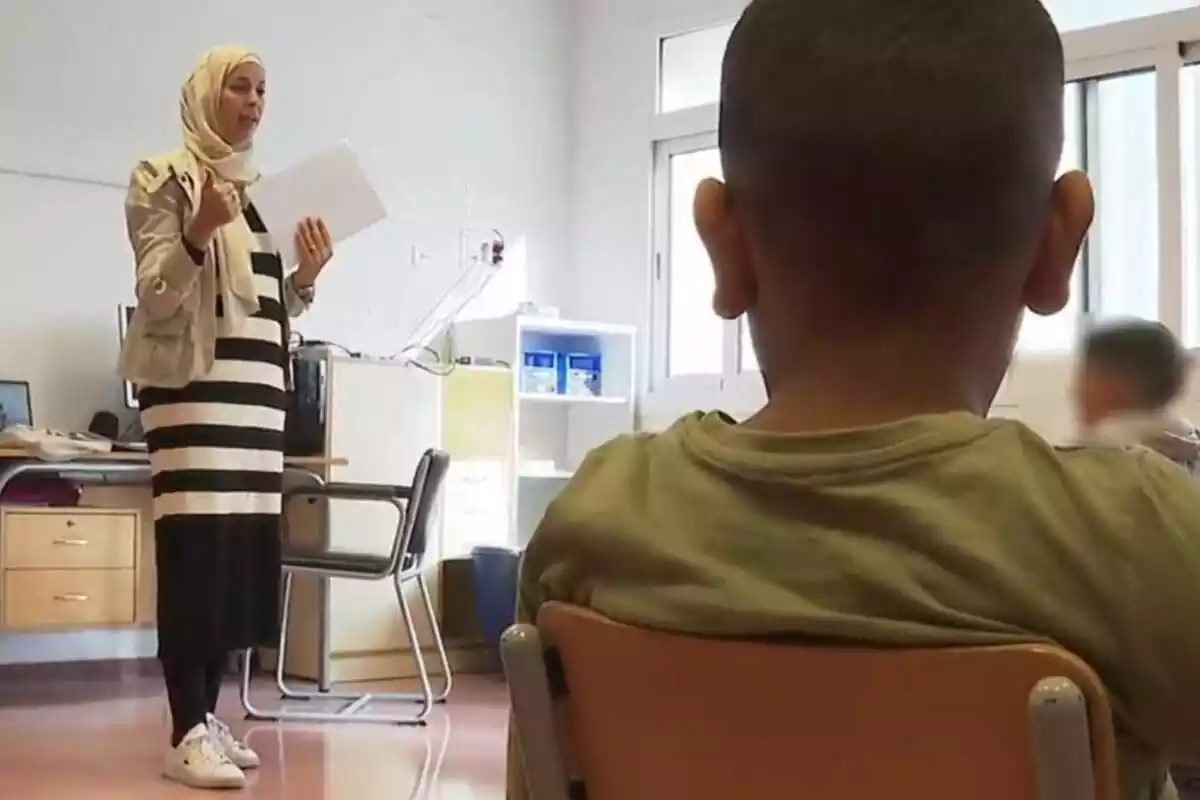 Captura d'una classe d'islam a una escola de Mallorca on surt una professora impartint classe vestida amb vel islàmic i en primer pla un nen d'esquena seguint les seves indicacions