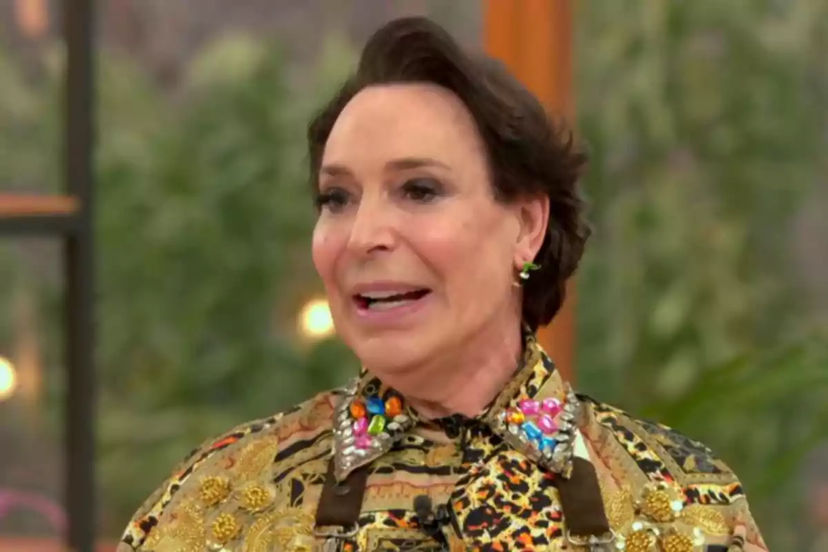 Benita porta una camisa amb un disseny acolorit i adornaments brillants, en un entorn interior amb fons desenfocat. Captura de 'Bake Off'. Benita porta una camisa amb un disseny acolorit i adornaments brillants, en un entorn interior amb fons desenfocat. Captura de 'Bake Off'.