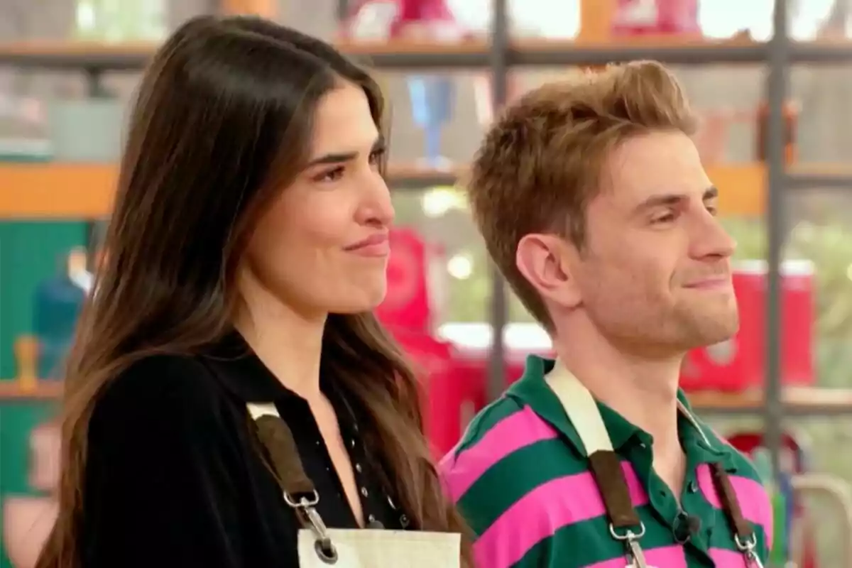 Lidia Torrent y Mario Marzo de pie, la mujer con cabello largo y el hombre con camiseta a rayas, ambos con delantales, en un entorno interior en 'Bake off: Famosos al horno'.