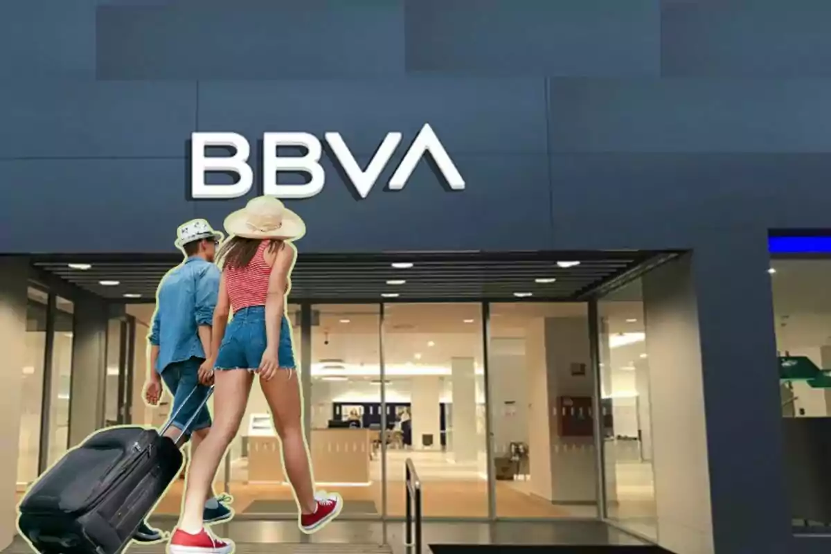 Dues persones amb maletes entrant a una sucursal de BBVA.