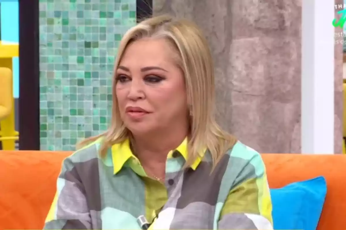 Belén Esteban, amb camisa de colors, asseguda en un sofà taronja al programa 'La família de la tele'