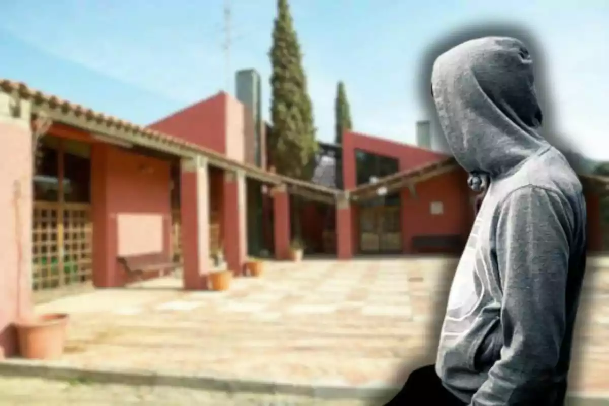 Un edifici de maó vermell amb un pati al davant i una persona amb dessuadora grisa amb caputxa de perfil.