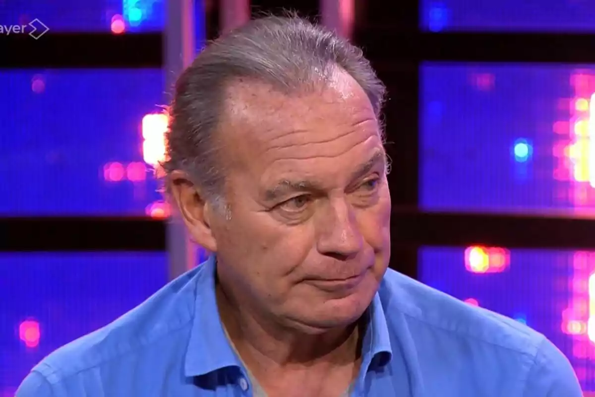 Bertín Osborne més gran amb camisa blava en un plató de televisió il·luminat amb llums de colors a Tu Cara Me Suena.