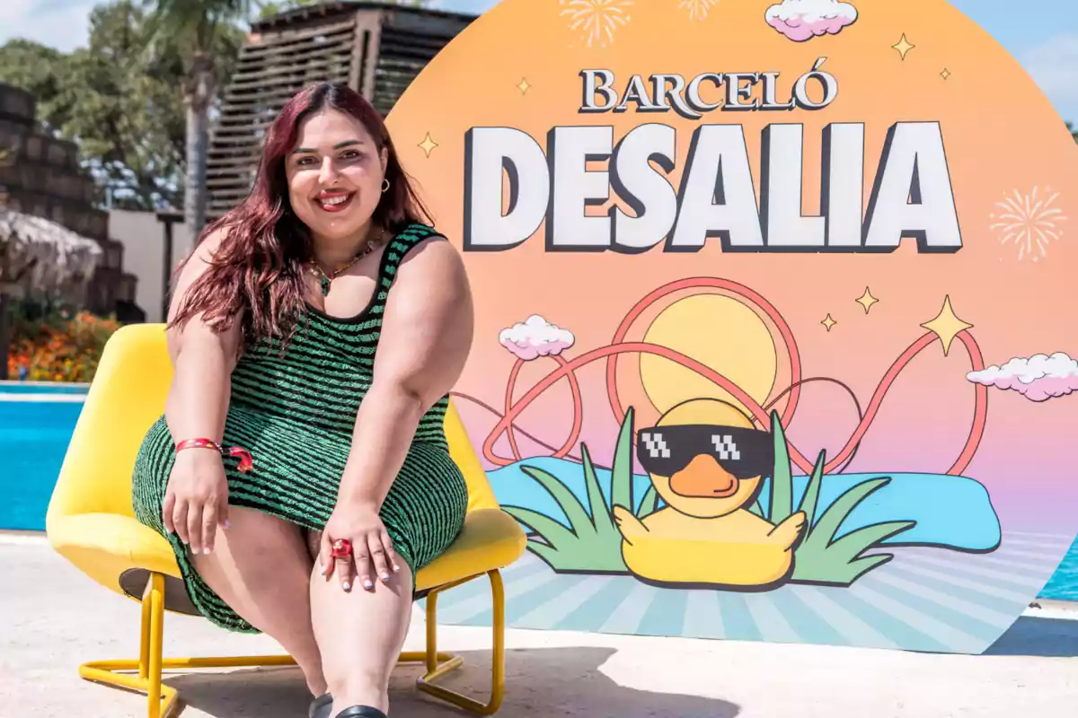 Blanca Martínez asseguda en una cadira groga davant d’un cartell colorit de Barceló Desalia amb un ànec animat amb ulleres de sol i una piscina al fons