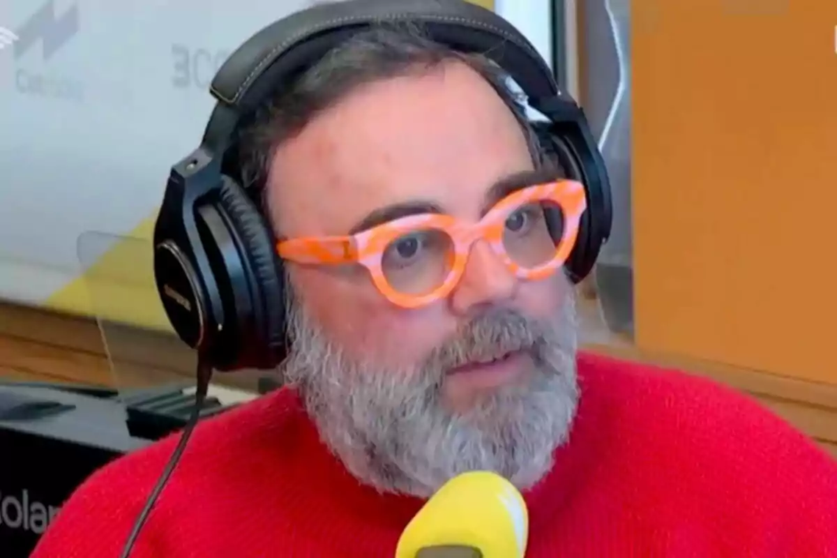 Bob Pop amb barba i ulleres taronges usant auriculars grans i un suèter vermell, parlant davant d'un micròfon groc en un estudi de Catalunya Ràdio.