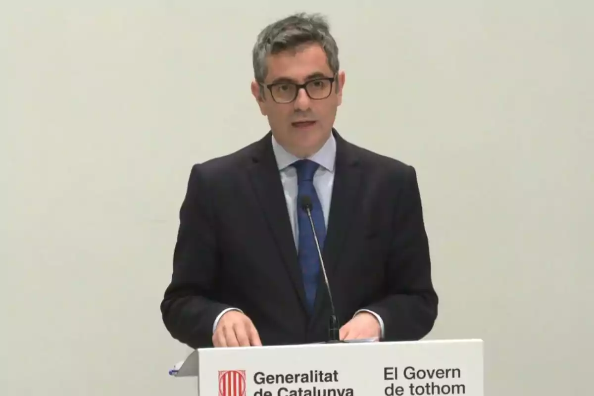 Un home amb ulleres i vestit fosc parla en un podi amb el logotip de la Generalitat de Catalunya.