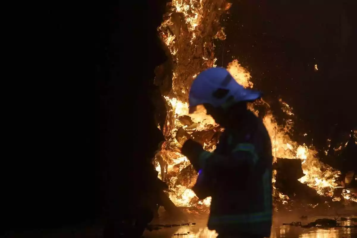 Un bomber, de perfil, amb un incendi de fons