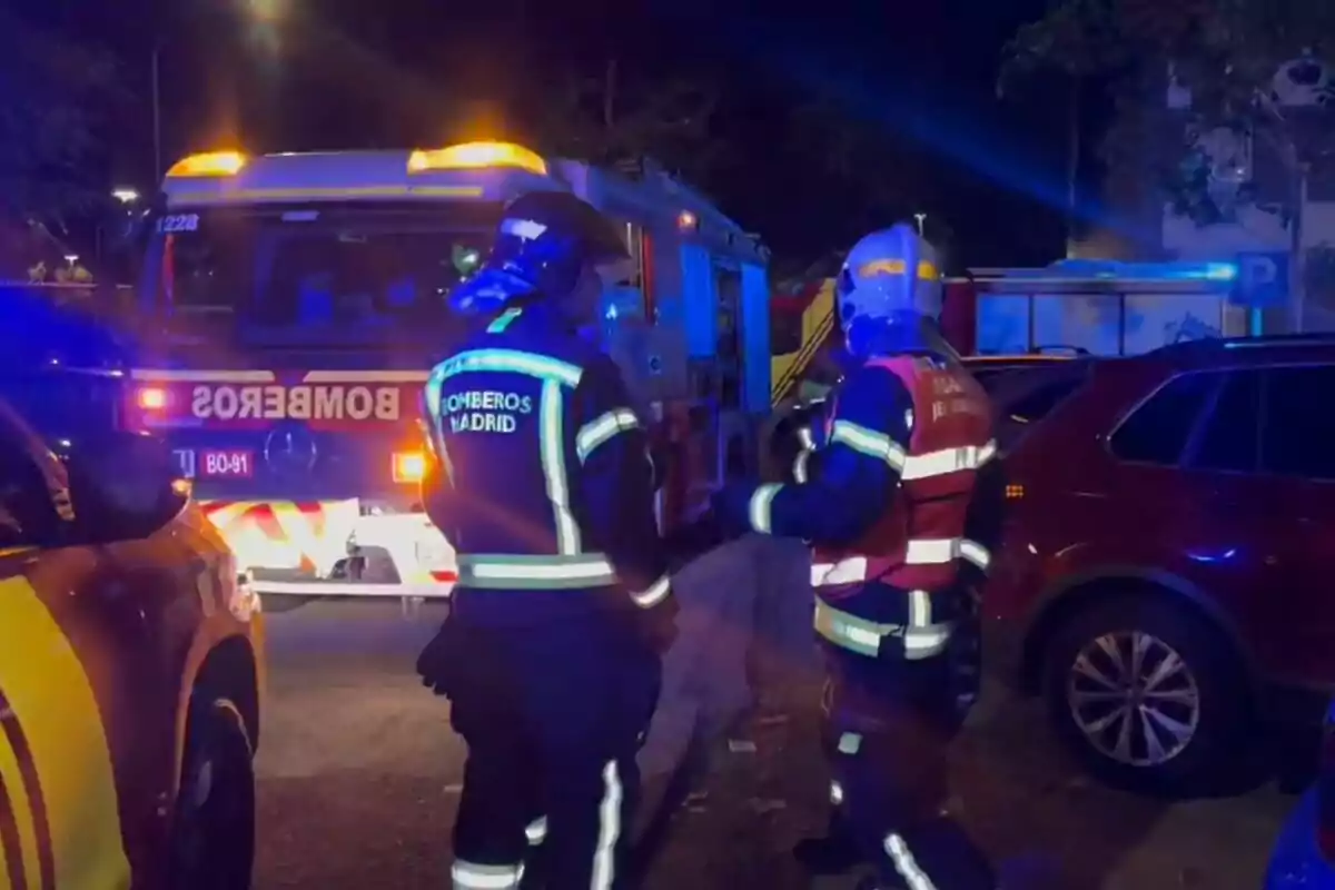 Bombers de Madrid treballant de nit amb un camió de bombers il·luminat.