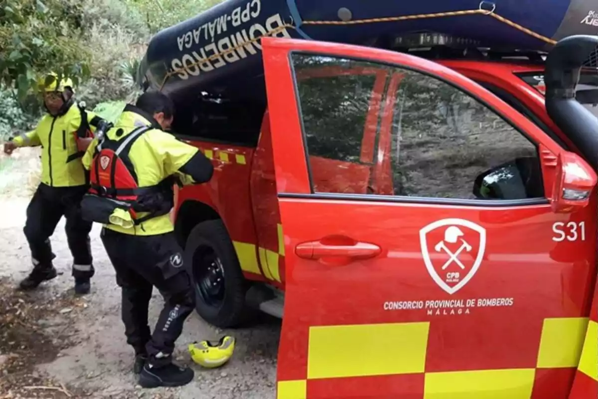 Bomberos del Consorcio Provincial de Málaga junto a un vehículo de rescate rojo con equipo de seguridad.