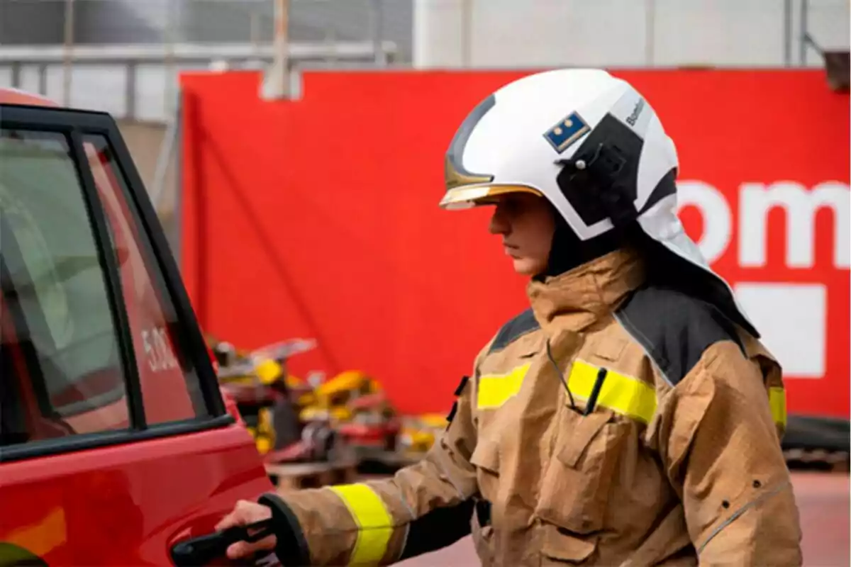 Firefighter in uniform and helmet opening the door of a red vehicle.