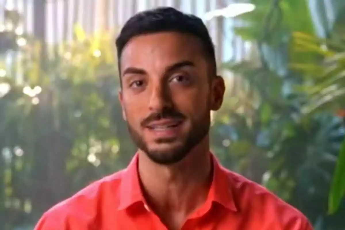 Borja González con barba y camisa roja posando frente a un fondo de vegetación en Supervivientes.