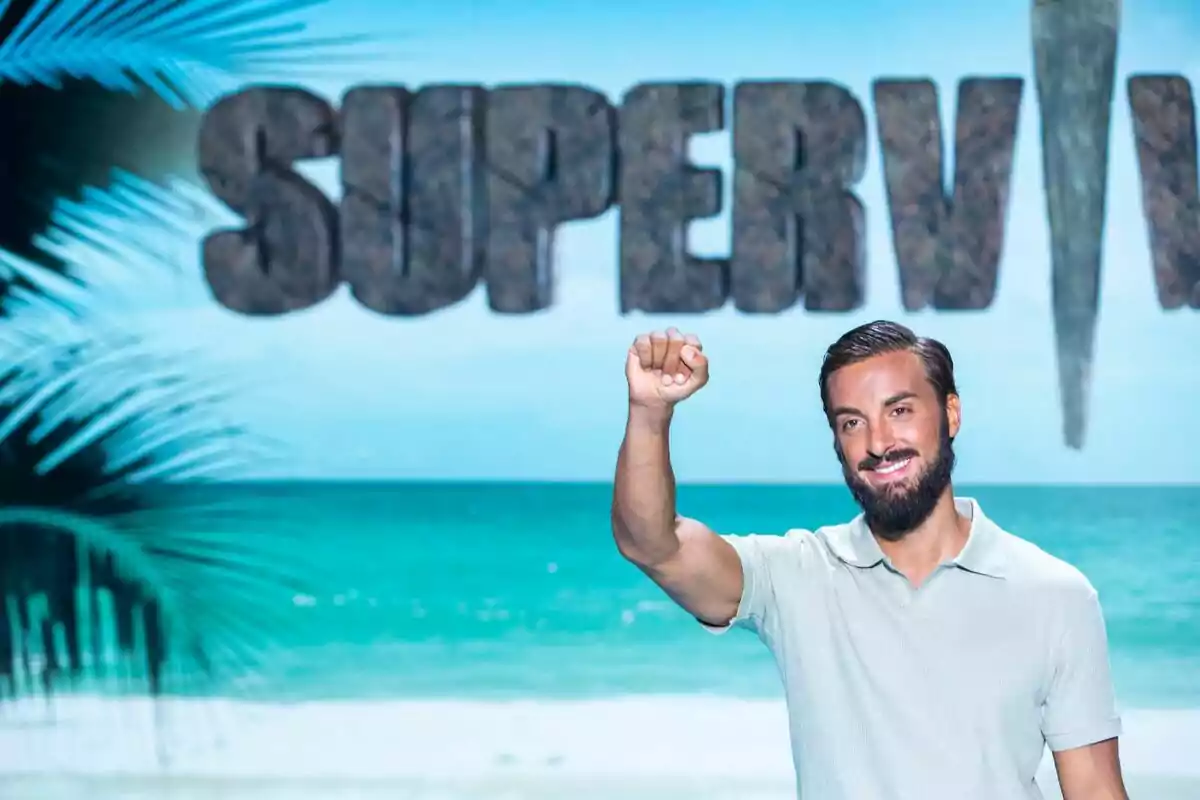 Borja González amb barba i samarreta clara somriu i aixeca el puny davant d’un fons de platja i el logotip de Supervivientes Borja González amb barba i samarreta clara somriu i aixeca el puny davant d’un fons de platja i el logotip de Supervivientes