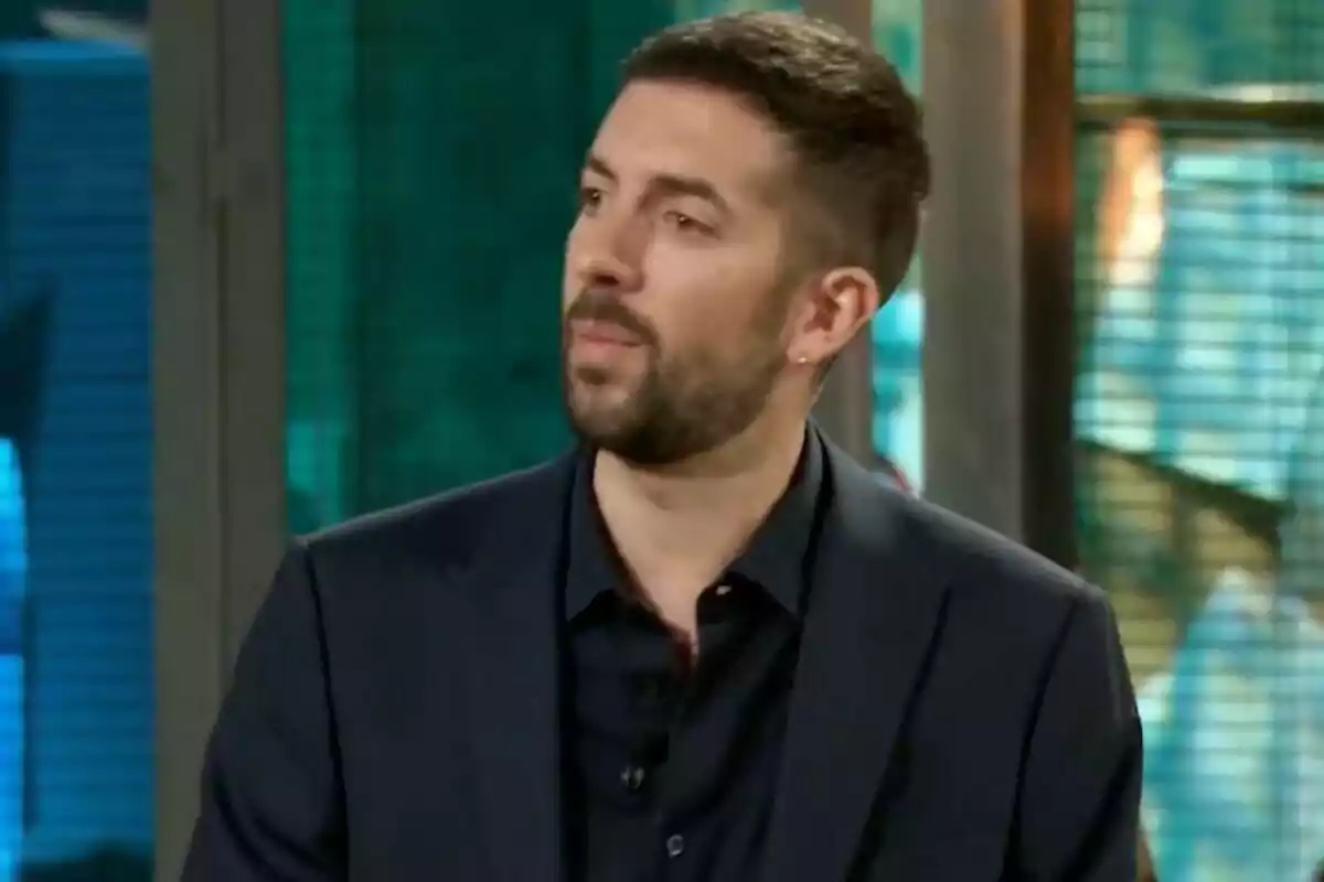 David Broncano amb barba curta i cabell fosc vestit amb americana negra en un ambient interior amb fons desenfocat a 'La Revuelta'.