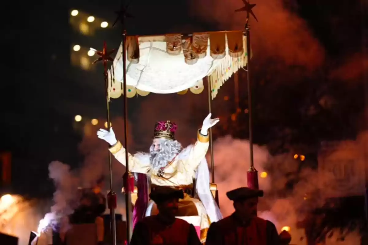 Un personatge disfressat de rei mag saluda des d'una carrossa il·luminada en una desfilada nocturna.