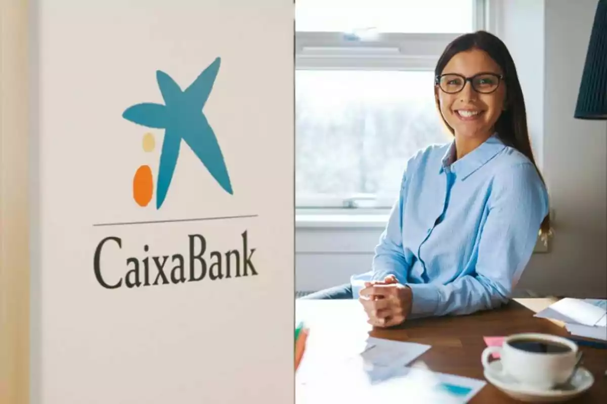 Una mujer sonriente con gafas y camisa azul sentada en un escritorio junto a una taza de café, con el logotipo de CaixaBank visible a la izquierda.