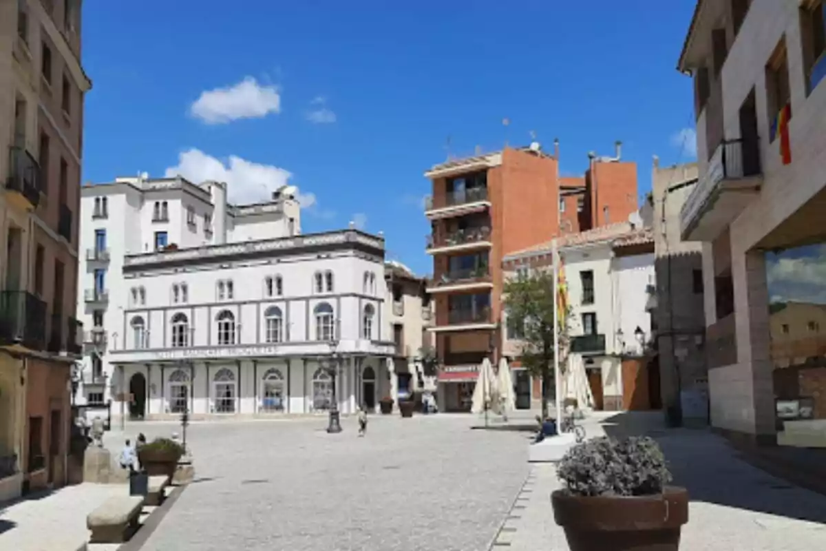 Plaza con edificios históricos y modernos bajo un cielo azul con algunas nubes.