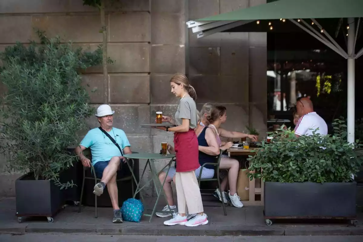 A waitress holds a tray in Barcelona's Plaza Real, June 15, 2022, in Barcelona, Catalonia, Spain.