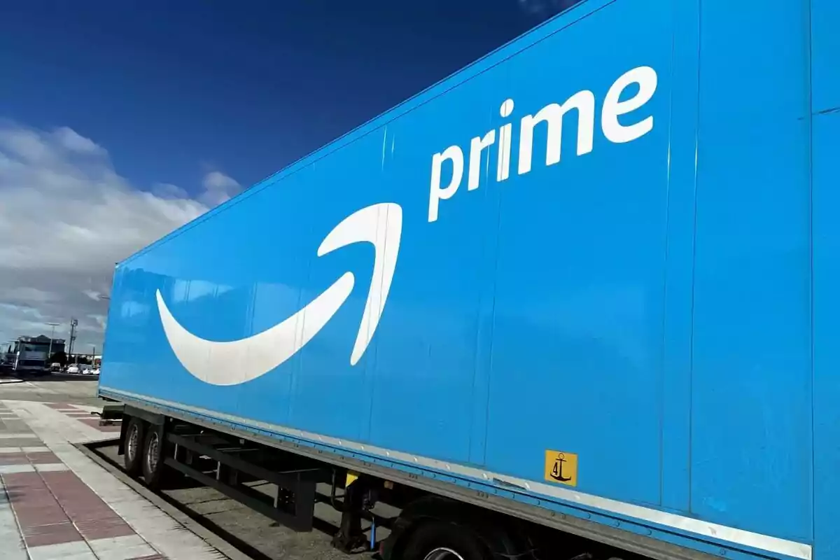 Un camión azul con el logotipo de Amazon en un estacionamiento bajo un cielo parcialmente nublado. Un camión azul con el logotipo de Amazon en un estacionamiento bajo un cielo parcialmente nublado.