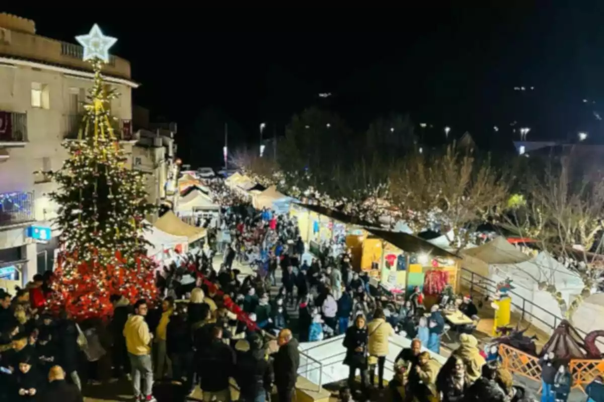 Una concorreguda fira nadalenca nocturna amb un gran arbre de Nadal il·luminat i parades decorades.