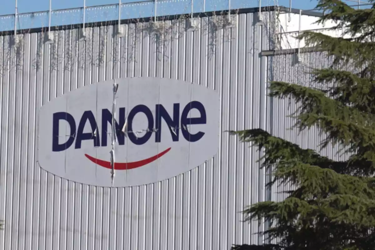 Imatge de l'exterior d'una fàbrica de l'empresa Danone amb el logotip de la marca en mida gran a la paret