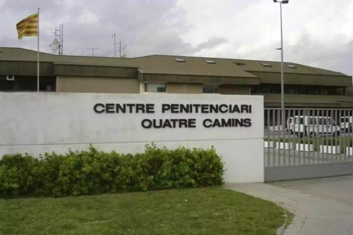 Entrada del Centre Penitenciari Quatre Camins amb una bandera catalana onejant en un pal i un edifici de fons.