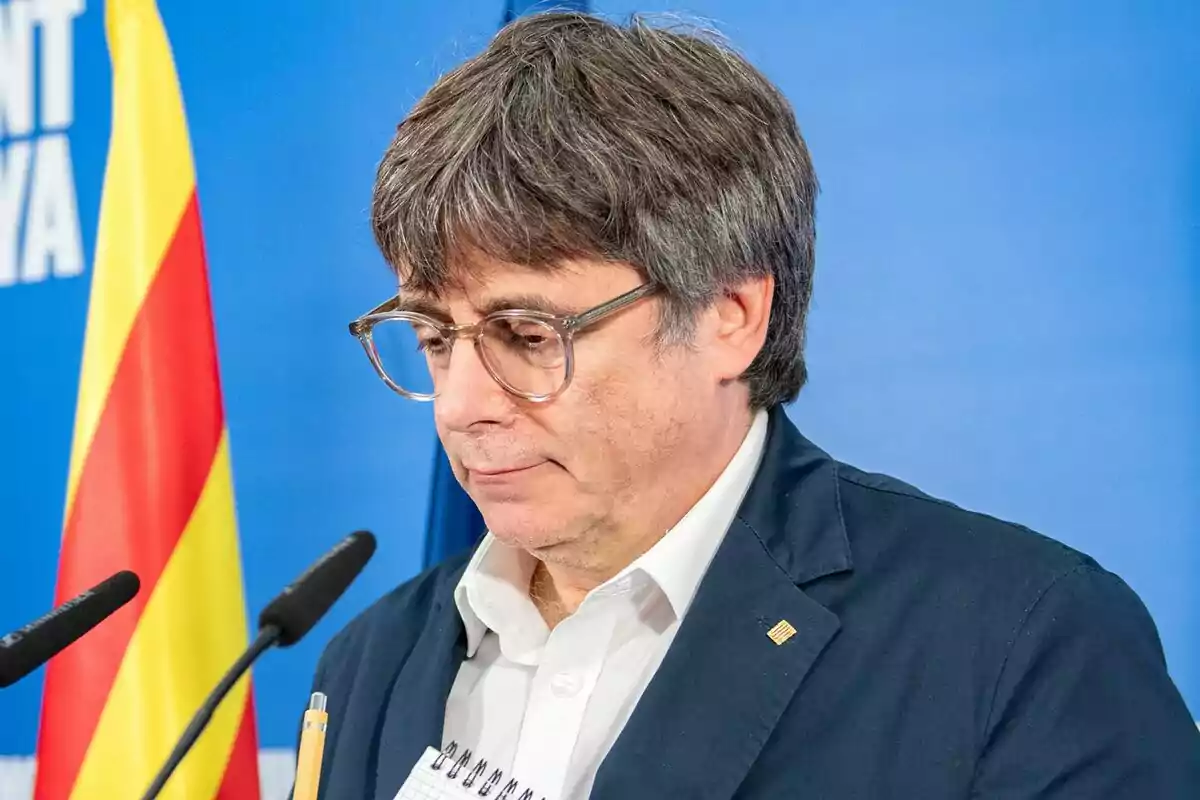 Carles Puigdemont a una conferència amb una bandera catalana de fons.