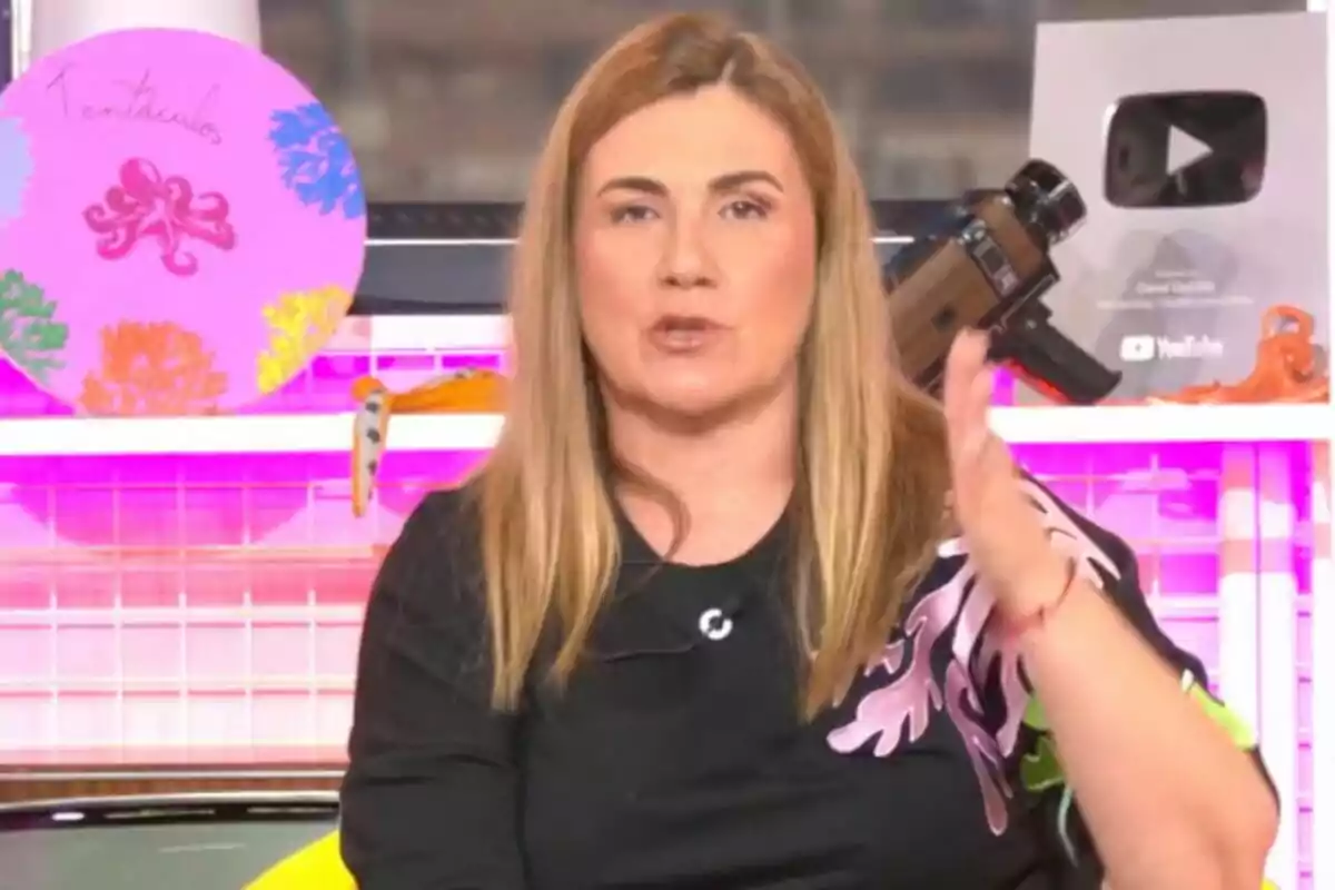 Carlota Corredera amb cabell ros llis parlant davant de la càmera amb una placa de YouTube i decoracions colorides de fons a 'Tentacles'