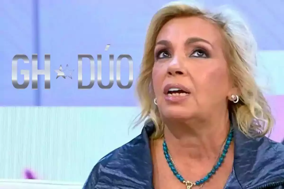 Carmen Borrego amb cabell ros i un collaret blau apareix en un programa de televisió amb el logotip de "GH DÚO" al fons.