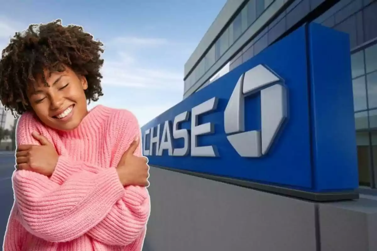 Una persona con un suéter rosa sonríe y se abraza a sí misma frente a un edificio con el logotipo de Chase.